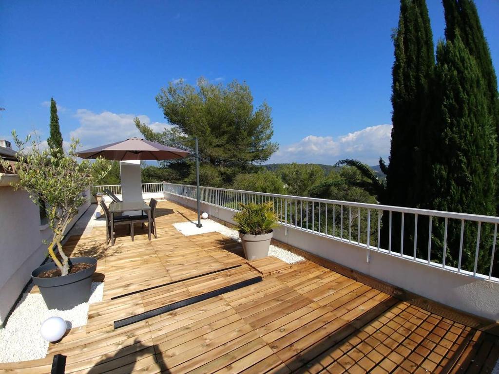 eine Holzterrasse mit einem Tisch und einem Sonnenschirm in der Unterkunft Suite l'Escoundudo in Aix-en-Provence