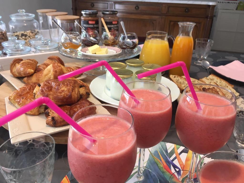 a table with three glasses of pink smoothies and pastries at Le jardin Chamberlin, Chambres d'hôtes in Savigny-sur-Orge