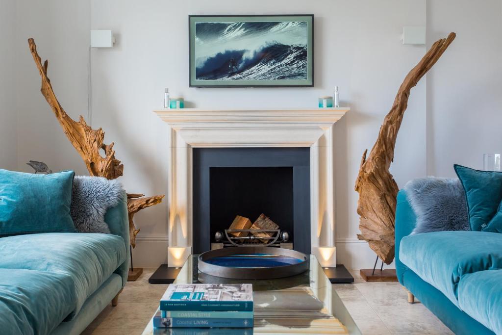 a living room with two blue couches and a fireplace at Merchants House in Salcombe