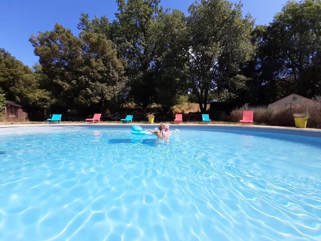 eine Person in einem Pool mit blauem Wasser in der Unterkunft Le Mas des 3 Anes in Blars