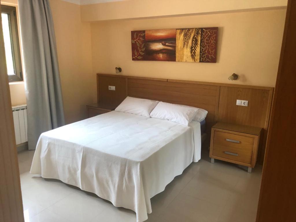 a bedroom with a white bed and a painting on the wall at hotel la Ribera in Santianes