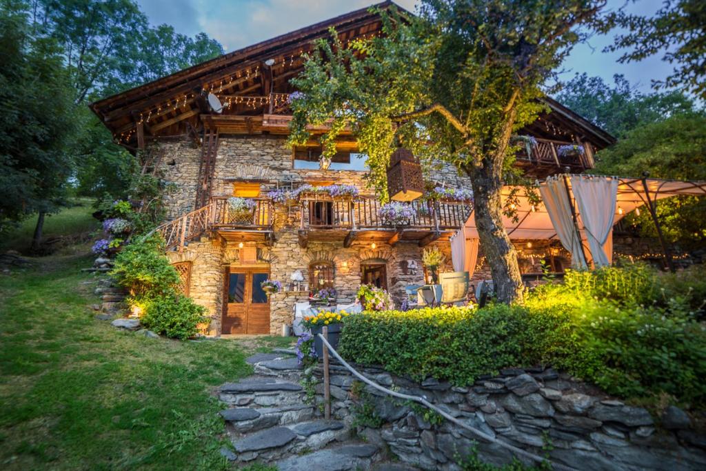 a stone house with a balcony and a tree at La Ferme d'Angele in Bourg-Saint-Maurice