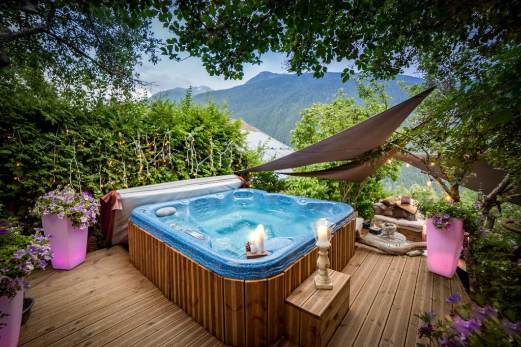 - un bain à remous sur une terrasse avec un parasol dans l'établissement La Ferme d'Angele, à Bourg-Saint-Maurice