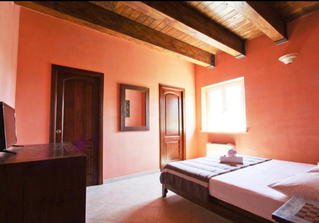 - une chambre avec des murs orange, un lit et une fenêtre dans l'établissement Dal Centurione, à Rome