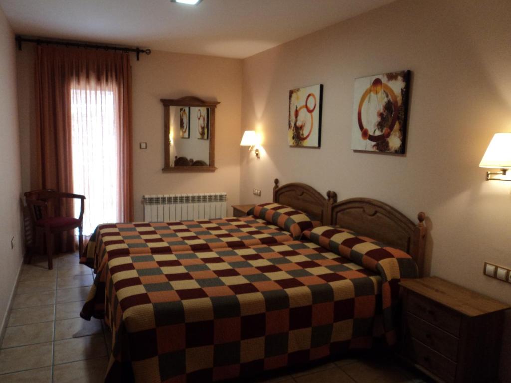 1 dormitorio con 1 cama con manta a cuadros en Apartamentos Solans, en Bielsa