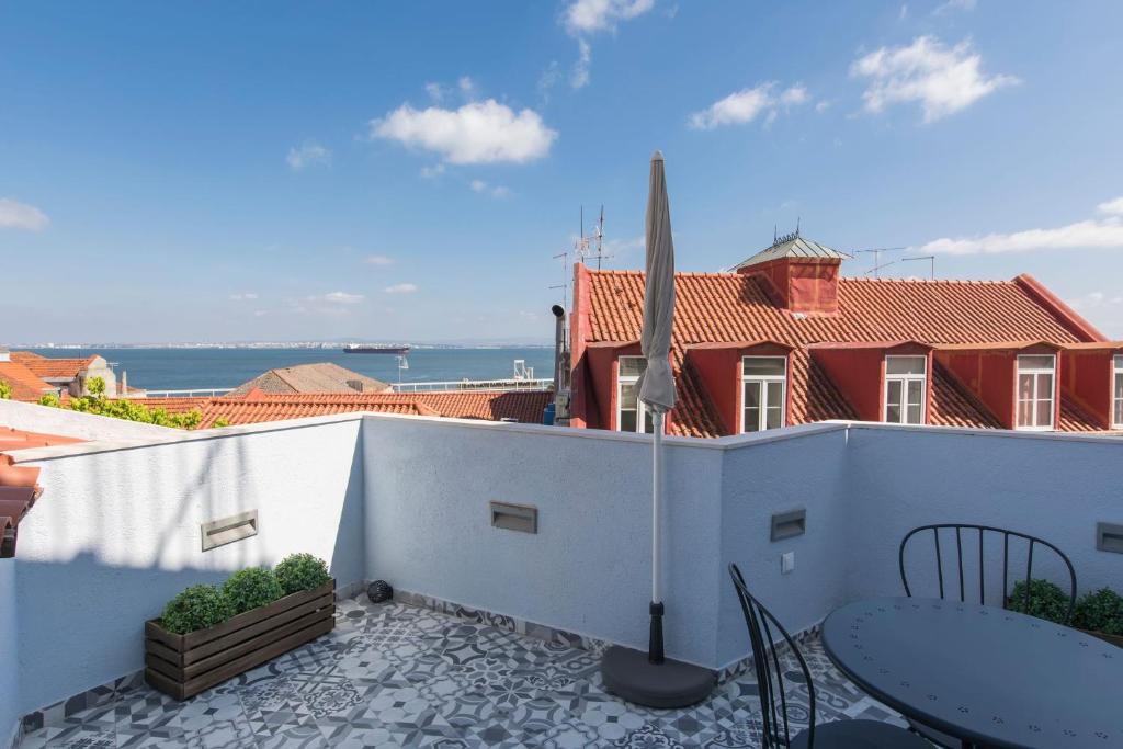 d'un balcon avec une table et des chaises et une maison rouge. dans l'établissement Terrace & River View in Alfama, à Lisbonne