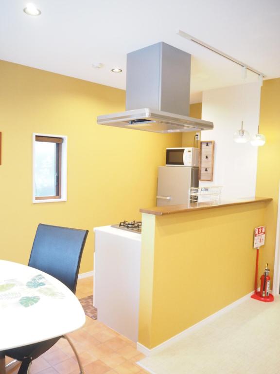 新潟市にあるGUEST HOUSE BOSTONSの黄色の壁のキッチン(テーブル、カウンター付)