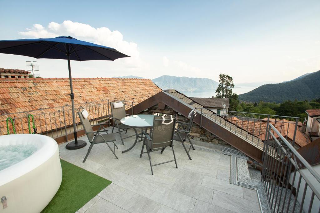 Trarego的住宿－La Casetta delle Ragazze Ribelli，阳台配有浴缸、桌子和雨伞。