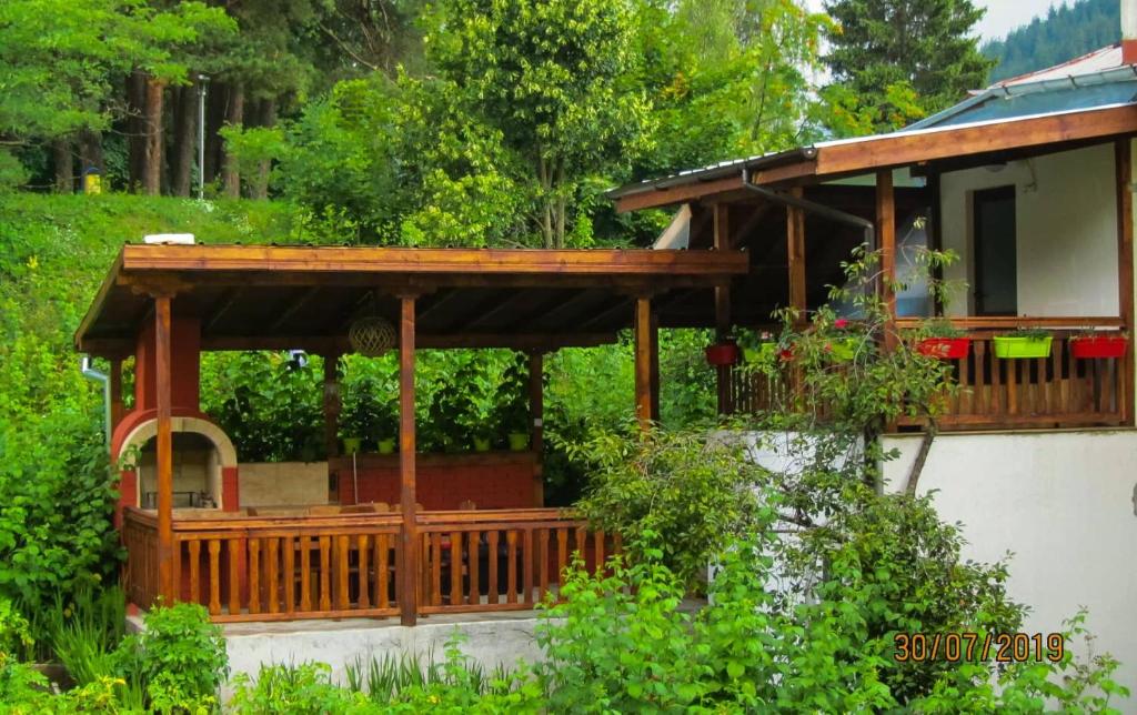 a wooden pergola on a house in a garden at Къща за гости Малините in Chepelare