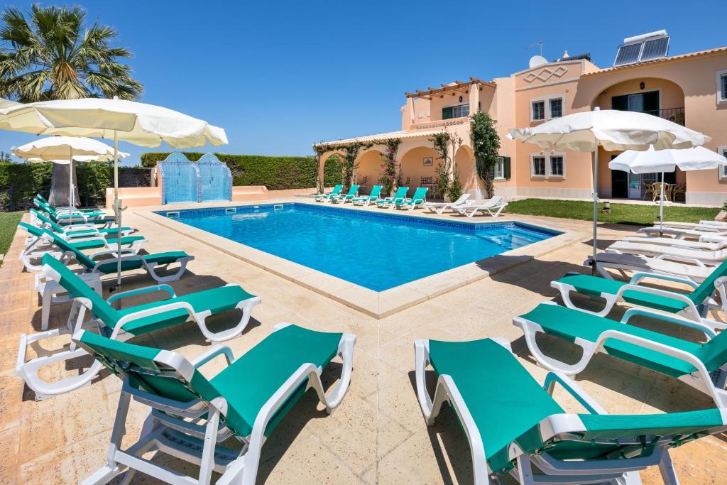una piscina con sillas y sombrillas frente a una casa en Apartamentos Monte dos Avós, Albufeira by AlgarveBlossom, en Albufeira