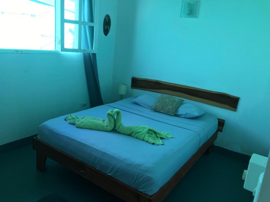 Un dormitorio azul con una cama con una manta verde. en green house two bedrooms, en Sámara