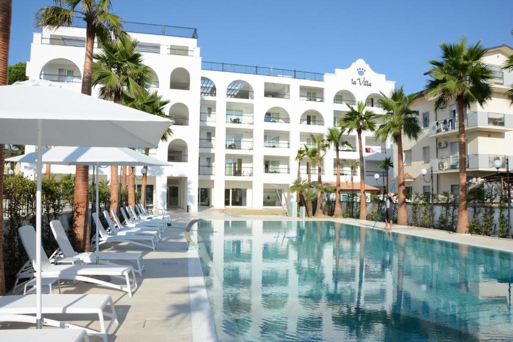 a swimming pool with chairs and umbrellas in front of a building at Residence La Villa in Tortoreto Lido