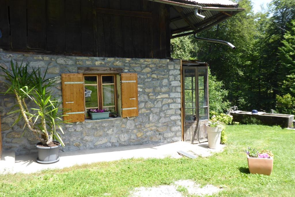 ein Steinhaus mit einem Fenster und Pflanzen im Hof in der Unterkunft L'Aire du temps Savoyard in Ugine