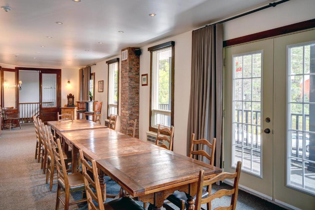 a large wooden table in a room with chairs and windows at Hotel Mont-Tremblant in Mont-Tremblant