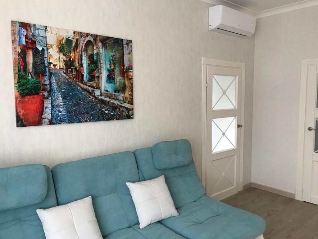 - un canapé bleu dans le salon orné d'une peinture murale dans l'établissement Апартаменты SILENA, à Oujhorod