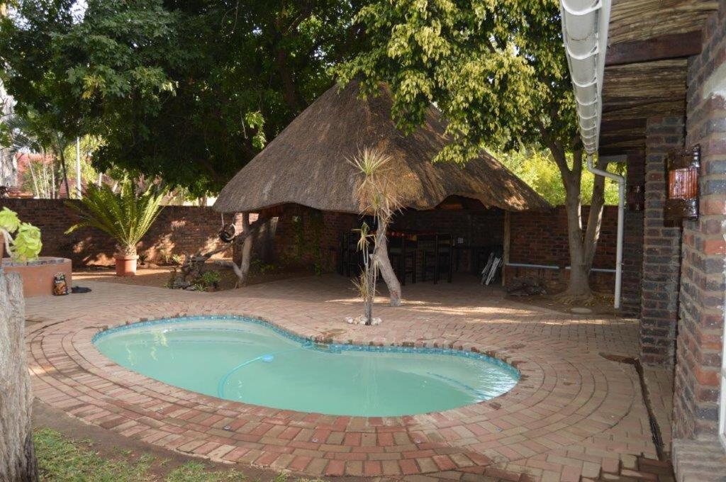 uma pequena piscina num pátio de tijolos com uma cabana em Villa Danamara em Phalaborwa