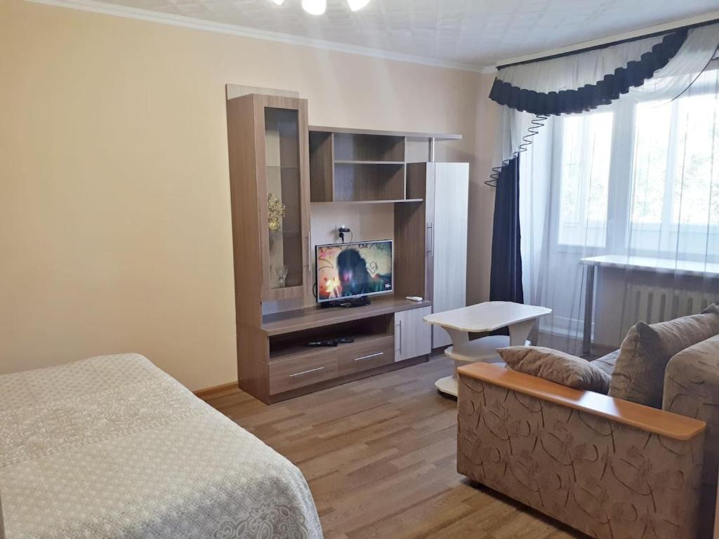 uma sala de estar com um sofá e uma televisão em Lux Apartment on Potanina 19 em Öskemen