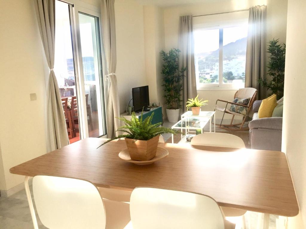 sala de estar con mesa de madera y sillas blancas en Valle Romano golf resort Capitolio Estepona, en Estepona