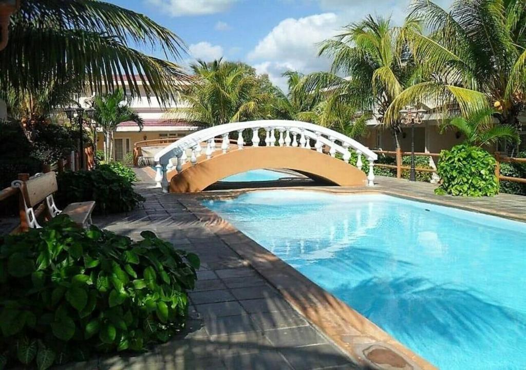 a bridge over a swimming pool next to a building at Bayview Villa Seaside in Flic-en-Flac