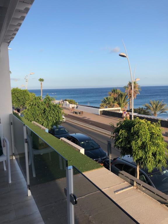a balcony with cars parked on a street and the ocean at Beach in Puerto del Carmen