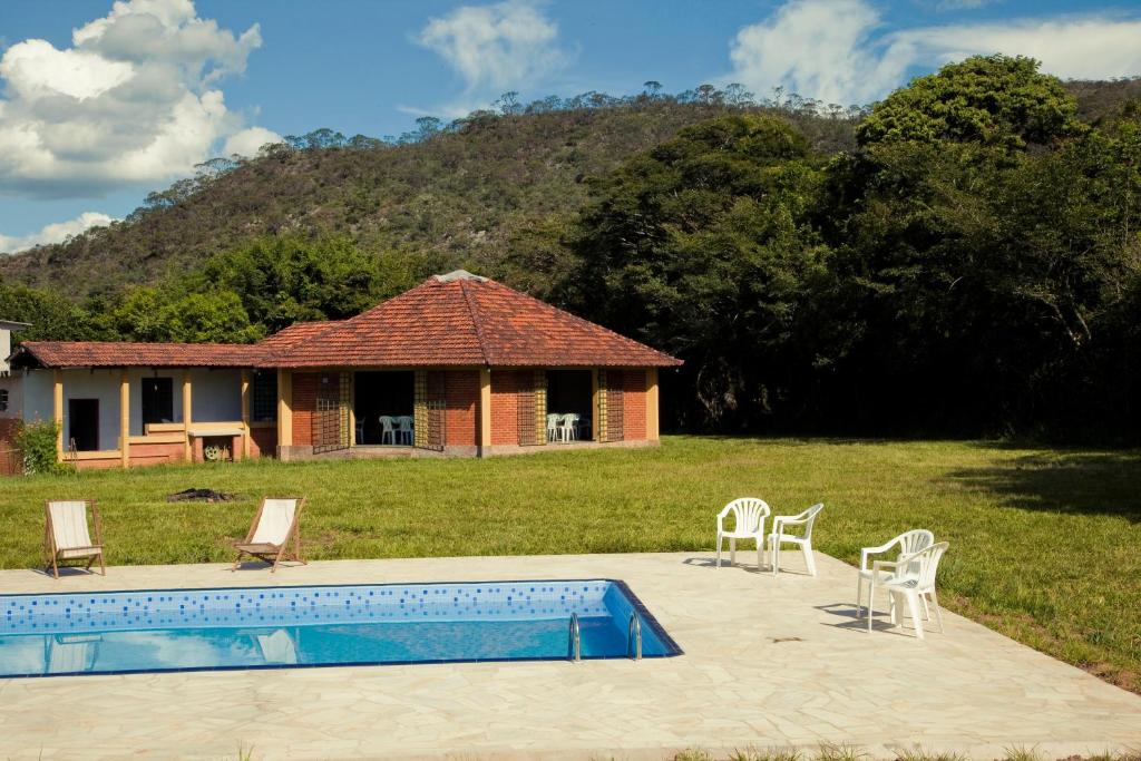 a house with a swimming pool and chairs in a yard at Pousada Soyndara in São Thomé das Letras