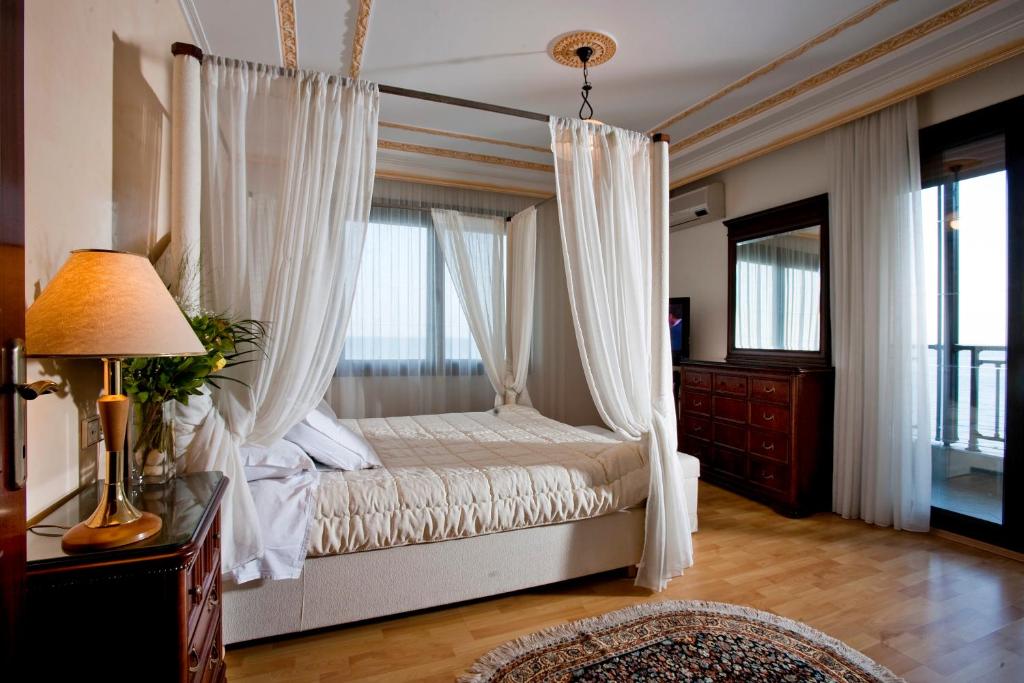 a bedroom with a canopy bed with white curtains at Kymata Hotel in Platamonas