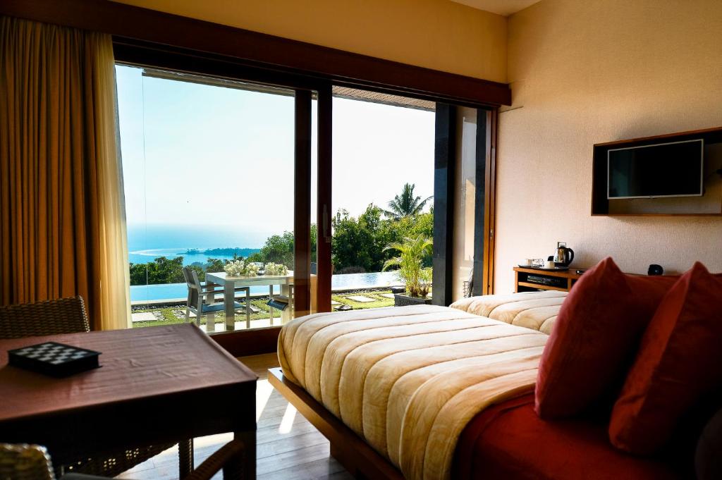 a hotel room with two beds and a large window at The Puncak Lombok in Senggigi