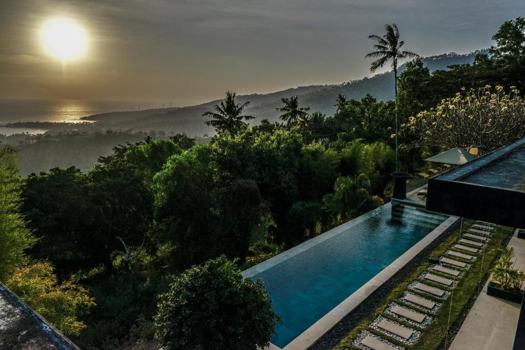 a house with a swimming pool and a view of the forest at The Puncak Lombok in Senggigi