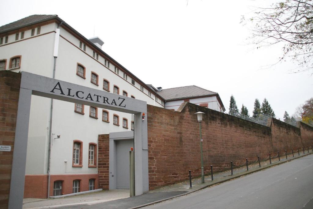 ein Gebäude mit einer Backsteinmauer neben einer Straße in der Unterkunft ALCATRAZ Hotel am Japanischen Garten in Kaiserslautern