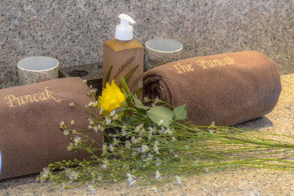 a bunch of flowers next to a bottle of soap and towels at The Puncak Lombok in Senggigi