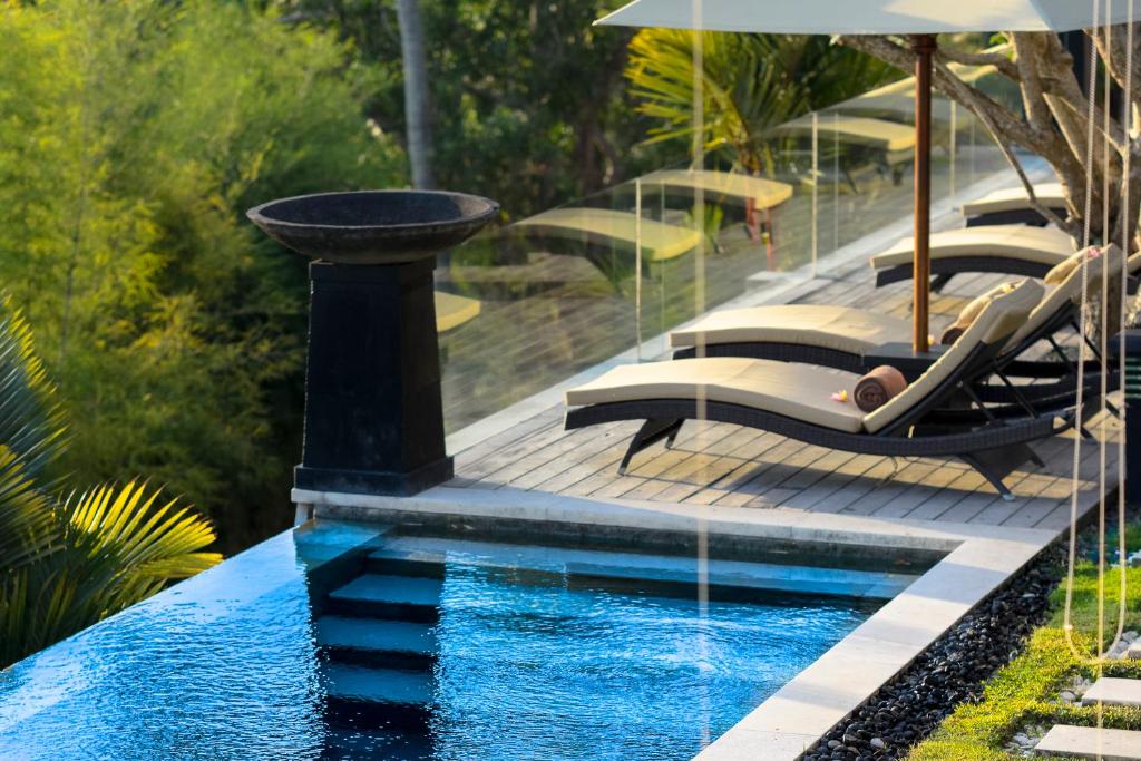 a swimming pool with lounge chairs and a fountain at The Puncak Lombok in Senggigi