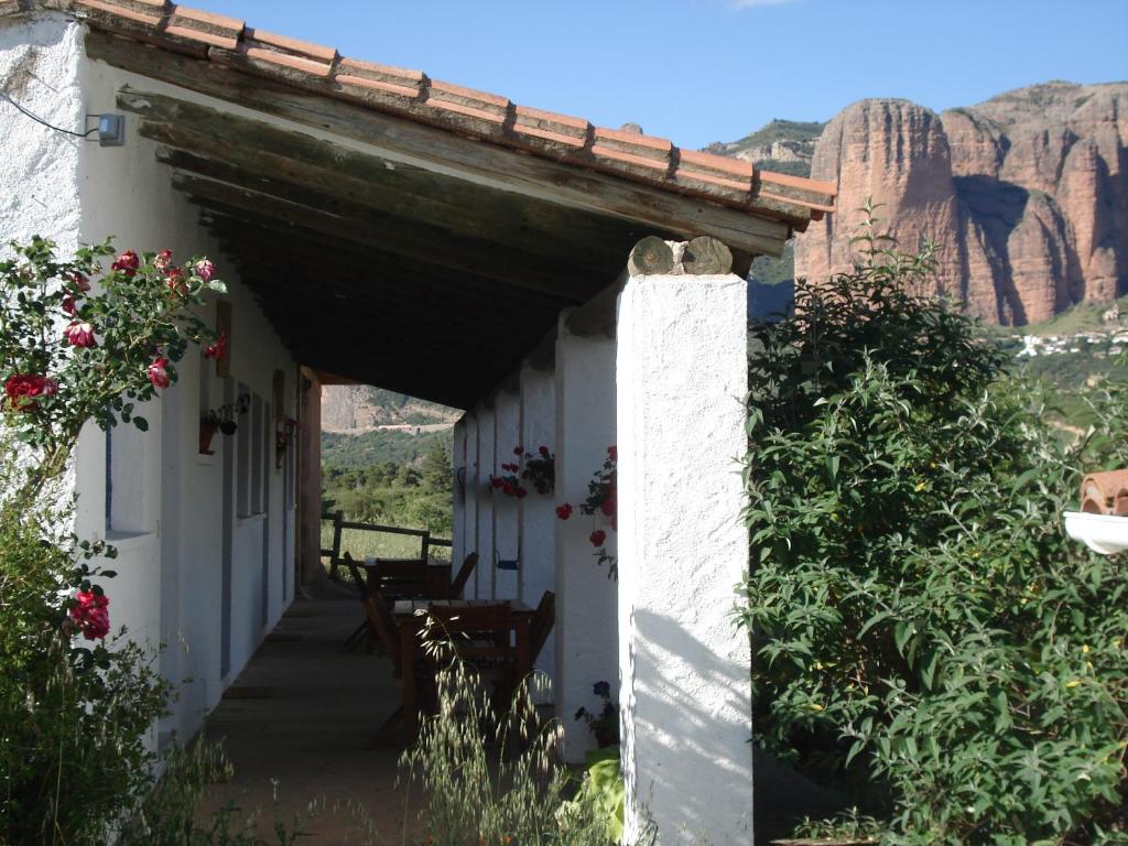 a white building with a porch with mountains in the background at Camping Bungalows Armalygal in Murillo de Gállego