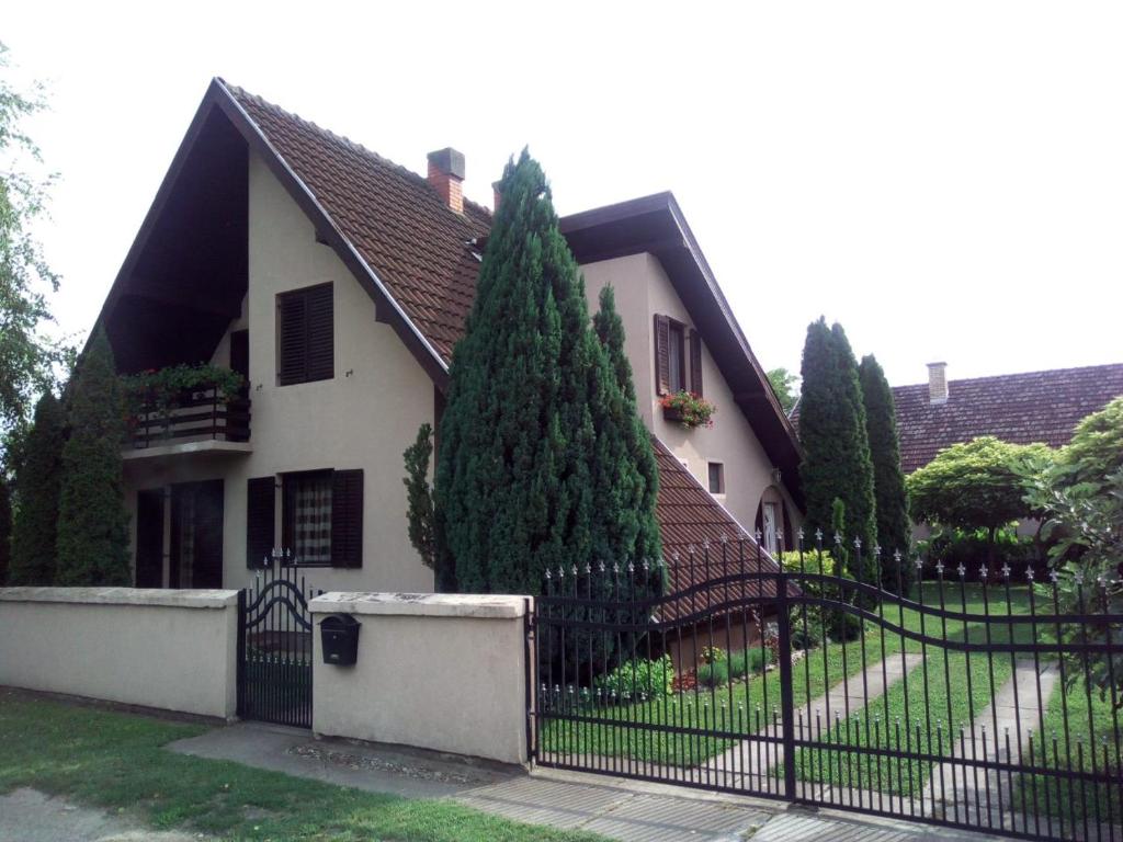 a house with a black fence and a tree at Villa Nirvana in Palić