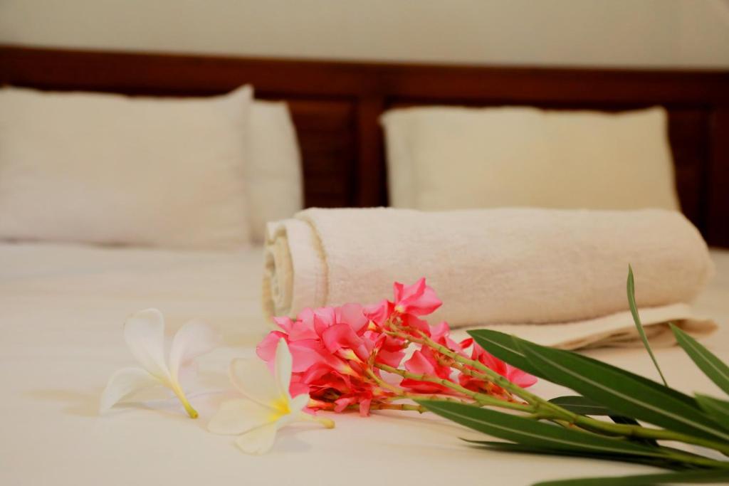 Una cama con una toalla y flores. en Nisala Guest, en Galle