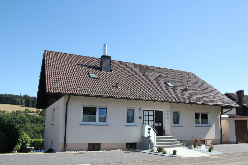 a white house with a brown roof at Ferienwohnung Abersfelder mit Balkon in Wildflecken