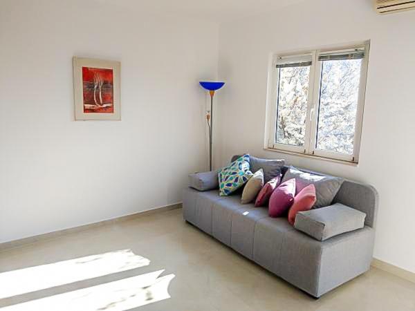 a living room with a gray couch with pillows at Luka 3 in Podgora