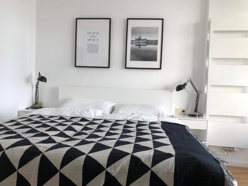 a bedroom with a black and white bed and two pictures on the wall at zentral gelegenes Ferienzimmer Möllner Seestrasse in Mölln