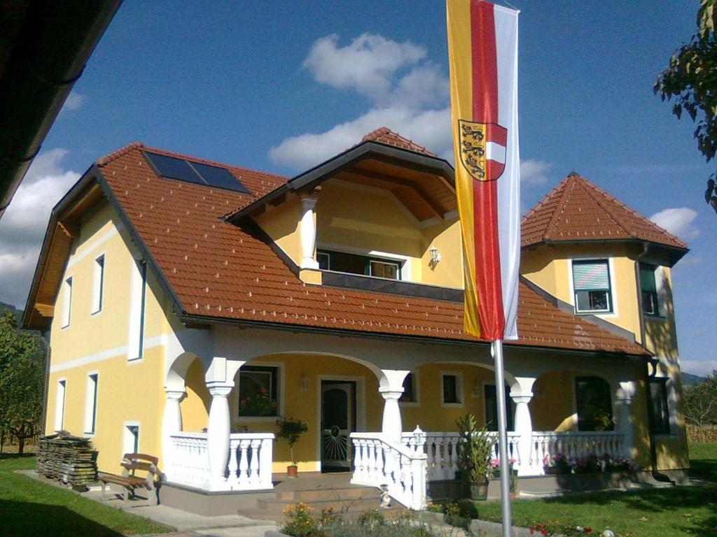 a yellow house with a red roof and a flag at Komfort Ferienwohnung Marina in Völkermarkt