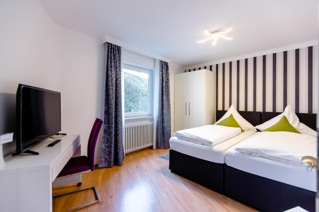 una habitación de hotel con una cama y un televisor en City Apartment an der Caracalla Therme, en Baden-Baden
