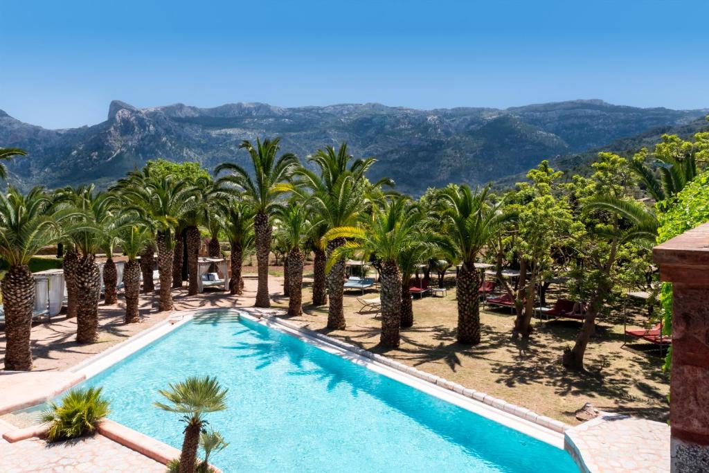 una piscina con palmeras y montañas al fondo en Hotel Finca Ca N'ai - Adults Only, en Sóller