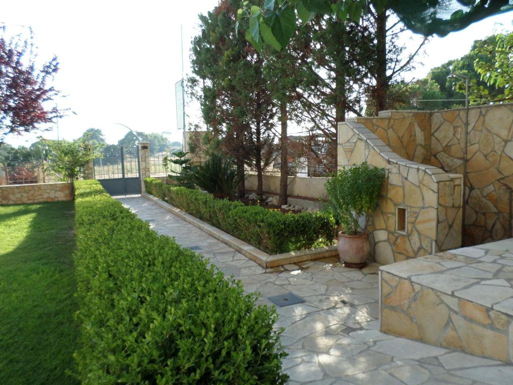 a garden with a stone fence and a stone walkway at Asfodelos Apartment Hotel in Kakovatos
