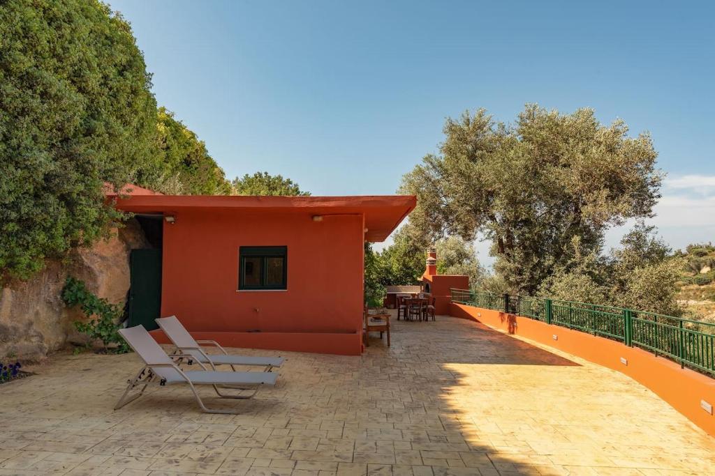 czerwony dom z patio i krzesłami przed nim w obiekcie Agapi's Home w mieście Roussospítion