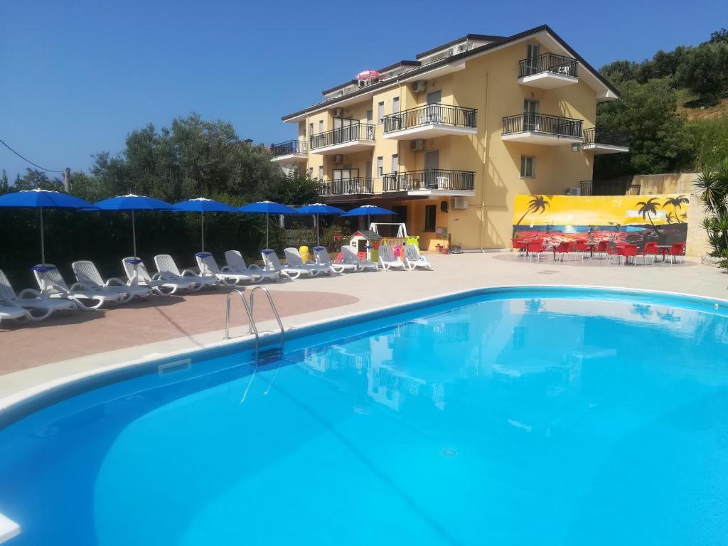 een zwembad tegenover een hotel met stoelen en parasols bij Hotel Le Mimose in Acquappesa