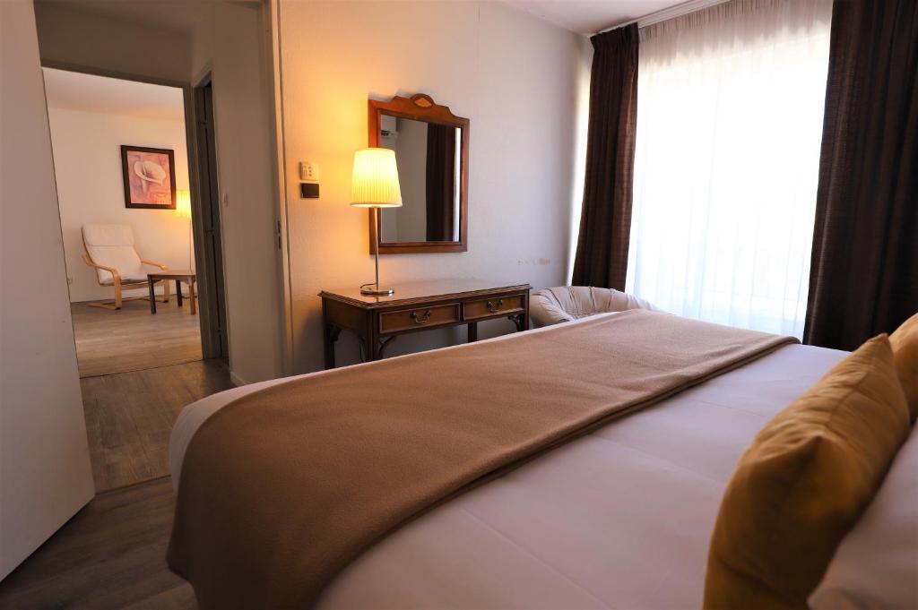 a bedroom with a bed and a mirror and a table at Hotel Des Tuileries in Nîmes