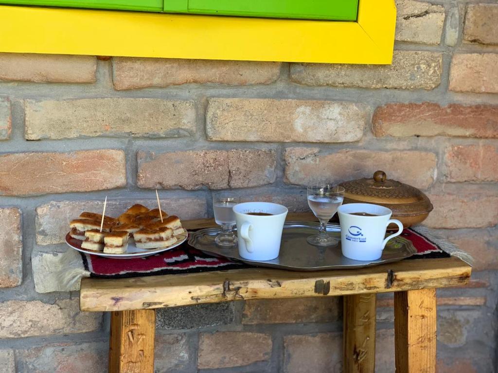 uma mesa com uma bandeja de produtos de pastelaria e chávenas de café em Etno apartman Tajna em Gornja Toplica
