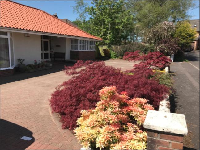 a garden of flowers in front of a house at The Clan Macfarlane Apartment in Kilmarnock