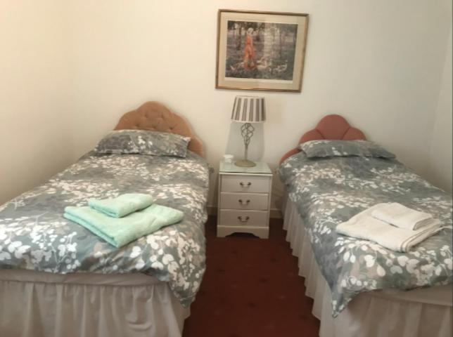 2 camas individuais num quarto com mesa de cabeceira em The Clan Macfarlane Apartment em Kilmarnock