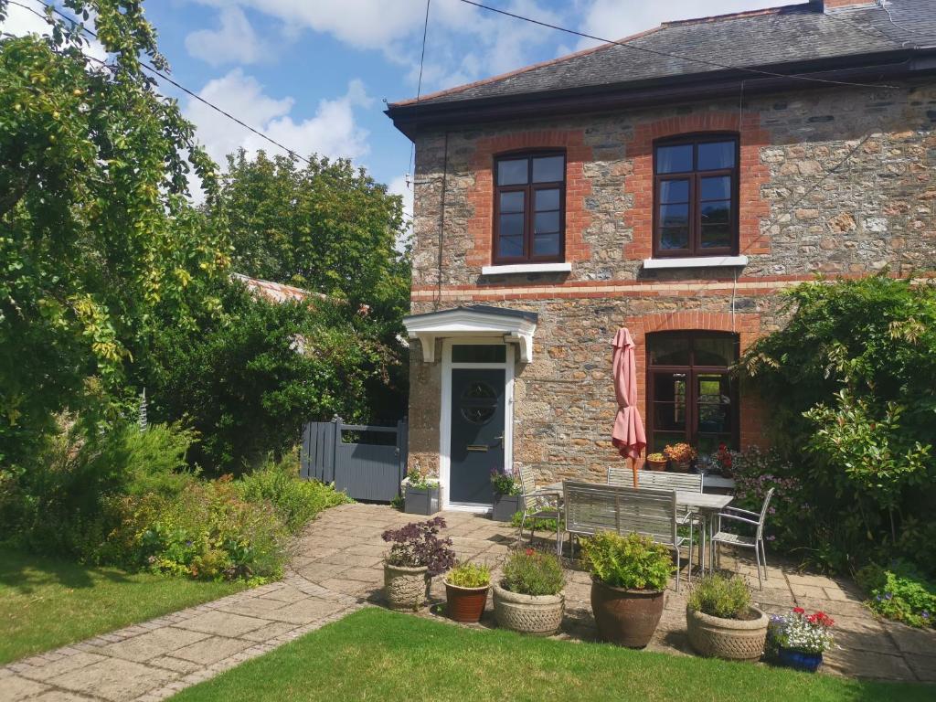 een stenen huis met een bank in de tuin bij Thornham Cottage in Ivybridge