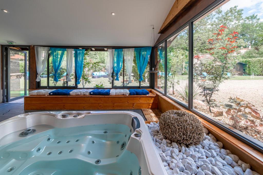 a jacuzzi tub in a room with windows at Hôtel Au Coq Dort Spa in Châtillon-sur-Chalaronne