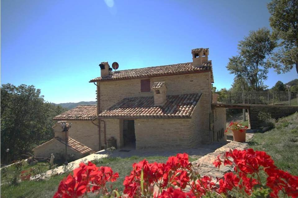 una casa con flores rojas delante de ella en Agriturismo il Casale del Barone, en Mercatello sul Metauro